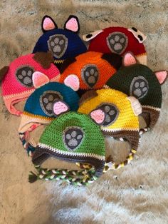 several knitted hats with animal ears and paws on them, all in different colors