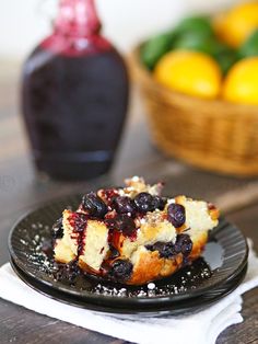 a piece of cake on a plate with blueberries and lemons in the background