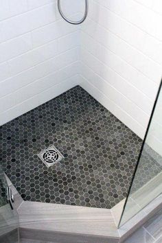 a bathroom with a shower stall and hexagonal floor tiles on the ground,