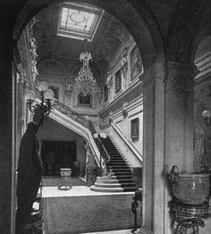 an old black and white photo of a staircase in a building with chandeliers