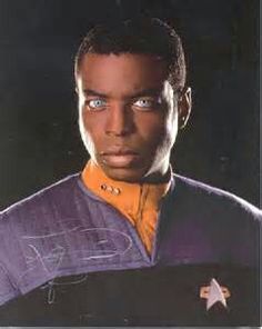 a close up of a person wearing a star trek uniform and looking at the camera