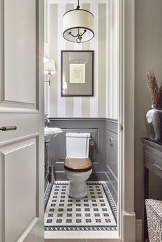 a bathroom with a toilet, sink and mirror on the wall next to an open door