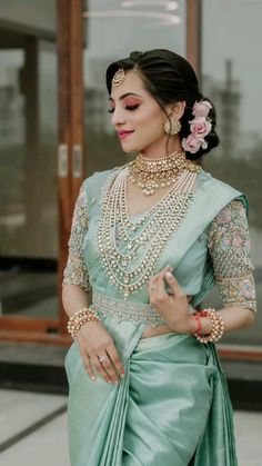 a woman in a green sari with pearls on her neck