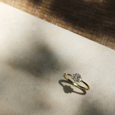 a diamond ring sitting on top of a piece of paper next to a shadow from the floor