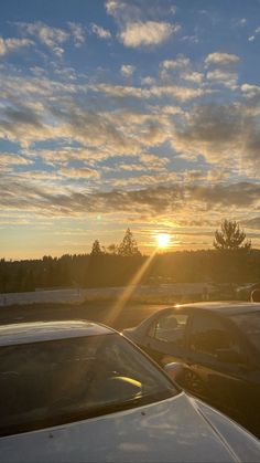 the sun is setting behind some parked cars