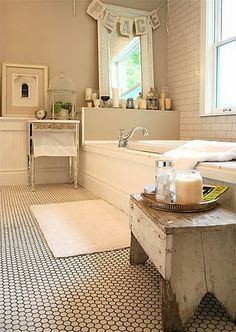 a white bathroom with black and white tile flooring on the walls, along with a bathtub