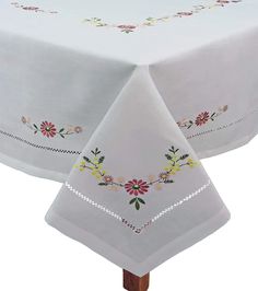 a white tablecloth with flowers on it and a cross stitched border around the edge