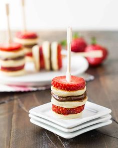 strawberry shortcakes stacked on plates with strawberries in the background