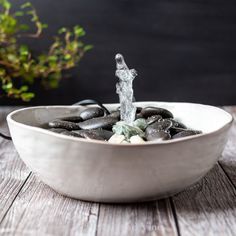 a bowl filled with rocks and water spouting out of it's side