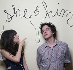 two people standing in front of a wall with writing on it