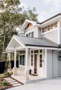 a white house with a black roof and steps leading up to the front door area