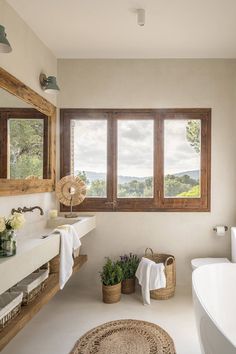 a bathroom with a large window, sink and bathtub next to a white tub