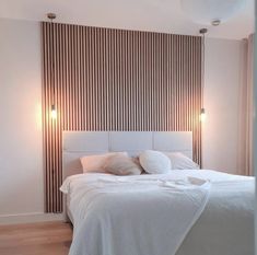 a white bed sitting in a bedroom next to a wall with vertical blinds on it