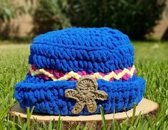 a crocheted blue hat sitting on top of a wooden stump in the grass