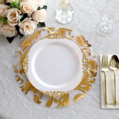 a white and gold table setting with silverware, flowers and napkins on it