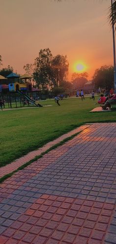 the sun is setting over a park with children's playgrounds in the background