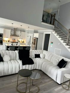 a living room with white couches and black pillows on the sofa, next to stairs