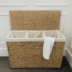 a wicker storage basket with two white towels hanging from it's sides and one folded towel on top