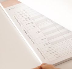 a person's hand is on top of a white paper with numbers and symbols