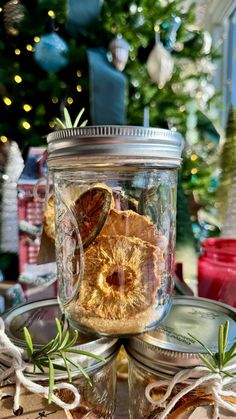 a glass jar filled with orange slices on top of a table next to a christmas tree