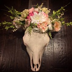 a cow skull with flowers in it on a wooden floor