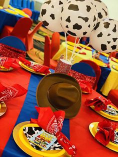 a table topped with plates and balloons in the shape of cows