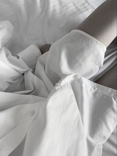 an unmade bed with white sheets and pillows