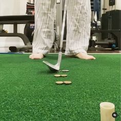 a man standing on top of a green field next to a pair of golf clubs