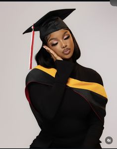 a woman wearing a graduation gown and holding her hand to her face while posing for the camera