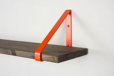 a wooden shelf with two orange brackets on it