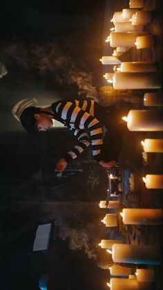 a man in striped shirt standing next to lit candles