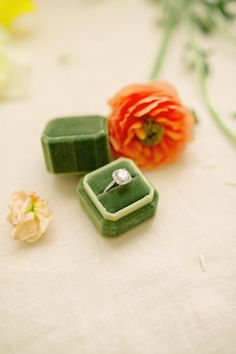 two pieces of jewelry sitting on top of a table next to flowers and a flower