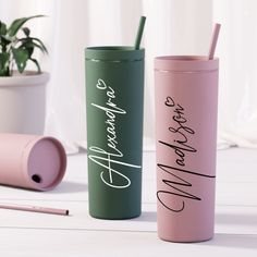 two different colored tumblers sitting next to each other on a white table with a plant in the background