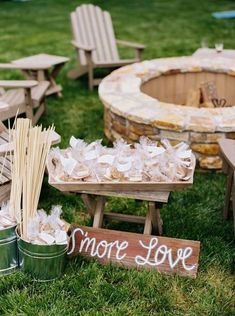 there are some chairs and other items in the grass near a fire pit with marshmallows on it