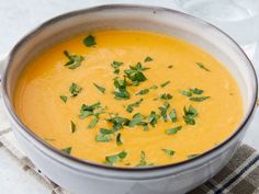 a white bowl filled with yellow soup and garnished with parsley on top