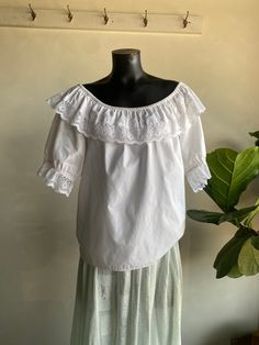 Vintage 1970s Malco Modes Square Dancing Puff Sleeve Lace Off Shoulder Blouse. White in color, made from a cotton/poly fiber blend. Off shoulder fit/design with puff sleeves and gorgeous lace detail throughout. Very soft and lightweight. Condition overall is great with only minor flaws that include; two small faint spots on front as shown in photos. No rips or tears. Please see all photos for details. Refer to measurements below to ensure a proper fit (modeled on a size medium mannequin) best fits a modern XL 23" pit to pit 14" neck opening (shoulder to shoulder) 26" in length Cottagecore Top With Lace Trim And Puff Sleeves, Cottagecore Puff Sleeve Top With Lace Trim, Cotton Peasant Top With Lace Trim For Daywear, Cottagecore Lace Trim Puff Sleeve Top, Cottagecore Puff Sleeve Top For Daywear, Vintage White Peasant Top With Puff Sleeves, Vintage Puff Sleeve Peasant Top For Summer, Vintage Cotton Peasant Top For Spring, White Cotton Peasant Top With Ruffles