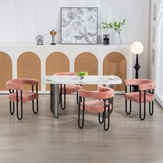 a dining room table with pink chairs around it