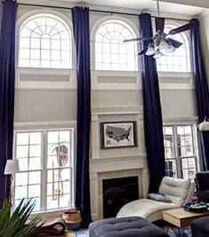 a living room filled with furniture and two windows covered in blue curtained drapes