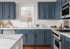 a kitchen with blue cabinets and marble counter tops