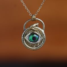 The Eye Inside The Snake, Snake Entwined Eye Necklace, Anaconda's Green Eye Necklace, Eyes Of Reptiles, 925K Sterling Silver Pendant, Gift My eye designs can be made specifically for your eyes, you need to take a beautiful iris photo for us. Then we can customize it for you. You can also add or remove blood details to our eye designs. You can write this in the order notes. Please send me a message after ordering. I can do as you wish. A quasi-universal symbol of protection, the evil eye is refer One Of A Kind Symbolic Sterling Silver Jewelry, Ceremonial Sterling Silver Hand Forged Jewelry, Antique Sterling Silver Hand Forged Necklaces, Antique Hand Forged Sterling Silver Necklaces, Antique Hand Forged Sterling Silver Necklace, Eye Designs, Luxury Jewelry Box, Green Eye, The Snake