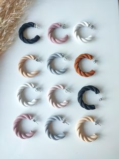 six pairs of hoop earrings on a white surface with dried grass in the back ground