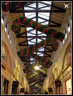 an indoor shopping mall decorated for christmas with lights and garlands hanging from the ceiling