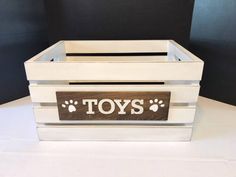 a toy box with the word toys written on it and paw prints in white paint