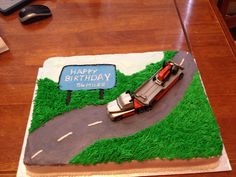 a birthday cake with a car on the road