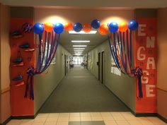 the hallway is decorated with balloons and streamers for an orange, blue, and white graduation party