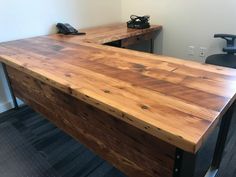 an office desk made out of wood with a phone on the table next to it