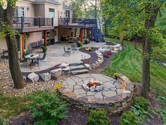 an outdoor fire pit in the middle of a yard with patio furniture and seating around it