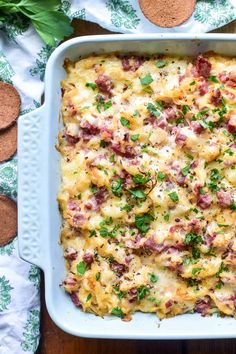 a casserole dish with meat and cheese in it on a wooden table next to crackers