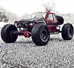 a red toy truck with big wheels on the road