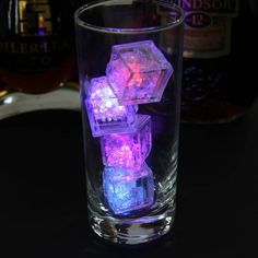 a glass filled with ice cubes sitting on top of a table